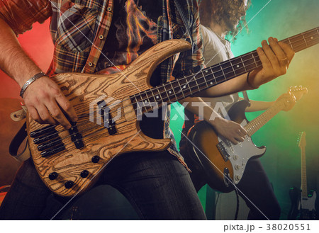 Rock band performs on stage. Guitarist, bass guitar and drums. 38020551