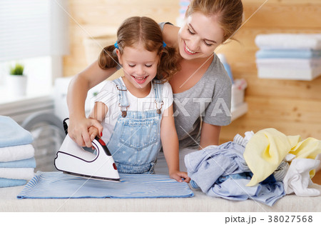 Happy family mother housewife and child daughter ironing clothes Happy family mother housewife and child daughter ironing clothes 38027568
