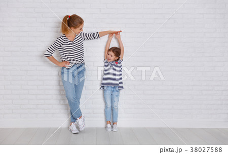 concept of the family. mother measures growth of child to daught 38027588