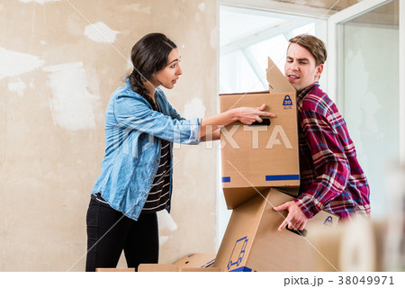 Young woman helping her partner to carry two boxes Young woman helping her partner to carry two boxes 38049971