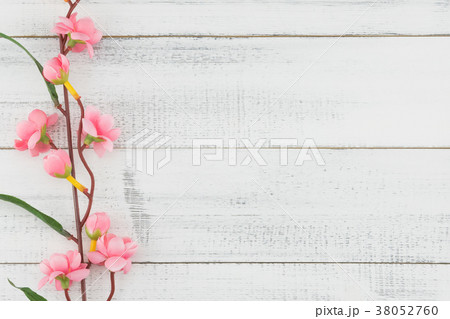 Fake pink flower branches on white wood Fake pink flower branches on white wood 38052760