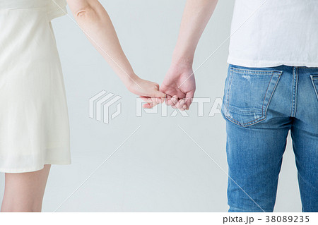 指をつなぐカップルの後ろ姿の写真素材