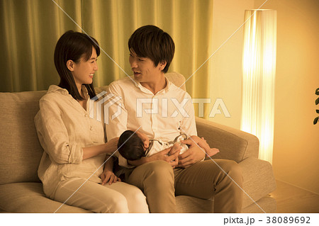 夜のリビングで赤ちゃんを抱く夫婦 38089692