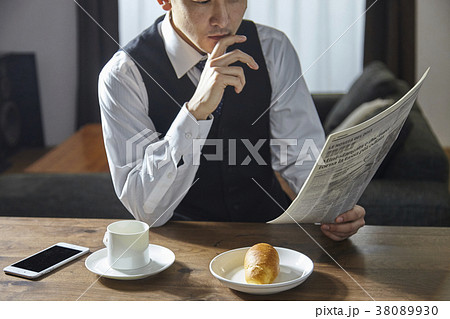 英字新聞を読みながらコーヒーを飲むお洒落なビジネスマン 38089930