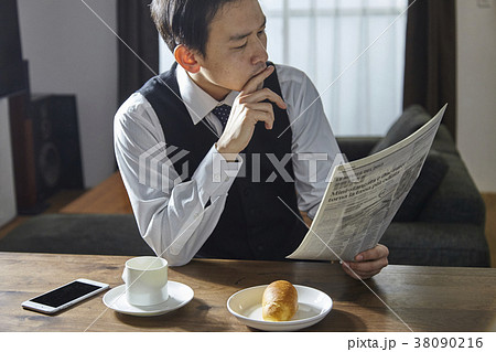 英字新聞を読みながらコーヒーを飲むお洒落なビジネスマン 38090216