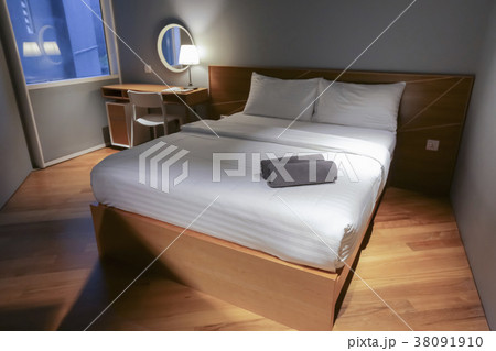 Bed in small simple hotel bedroom 38091910