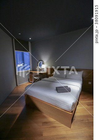 Bed in small simple hotel bedroom 38091915