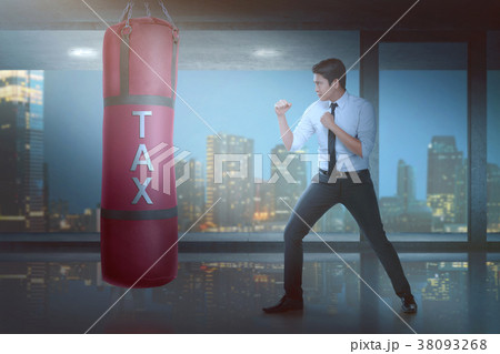 Powerful asian businessman puncing boxing heavy bag with tax sig Powerful asian businessman puncing boxing heavy bag with tax sig 38093268
