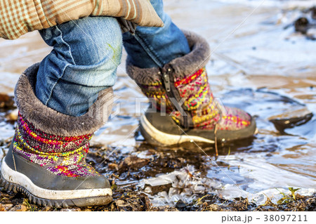 Child stands on icy dirty puddle Child stands on icy dirty puddle 38097211