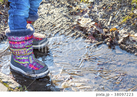 Child stands on icy dirty puddle 38097223