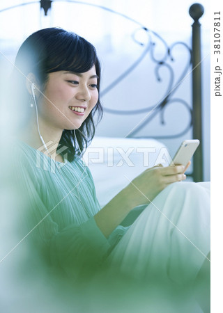 スマホとイヤホンで音楽を聴く女性 38107811