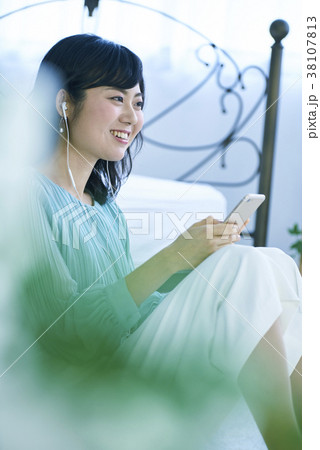スマホとイヤホンで音楽を聴く女性 スマホとイヤホンで音楽を聴く女性 38107813