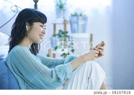 スマホとイヤホンで音楽を聴く女性 スマホとイヤホンで音楽を聴く女性 38107818