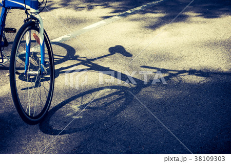 Bicycle wheel and shadow on bike lane in a park. Bicycle wheel and shadow on bike lane in a park. 38109303