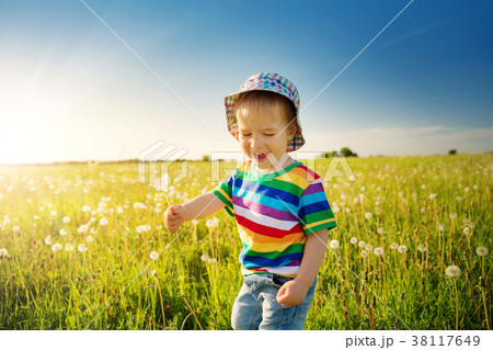 Baby boy standing in grass on the fieald with 38117649
