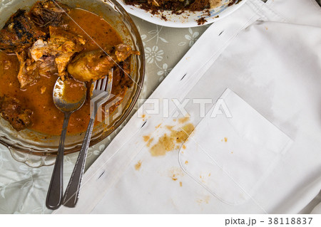Plate of curry chicken and white shirt with stain. 38118837