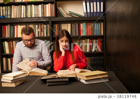 a man and a woman reading a book in the library 38119748