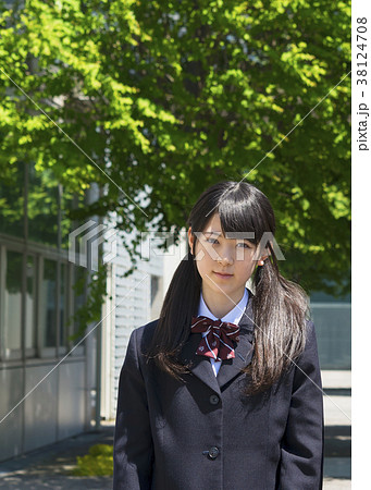 校舎の前に立つ制服を着た女子高生の写真素材