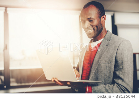 Elegant glad guy using device while standing Elegant glad guy using device while standing 38125044