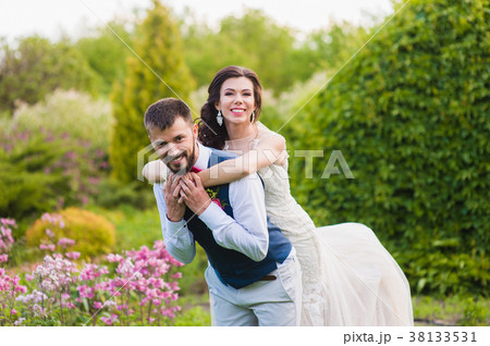 Bride hugs groom from the back on nature green 38133531