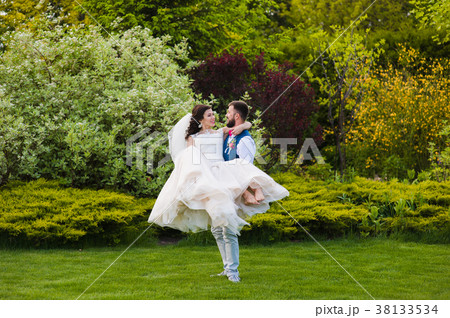 Smiling groom hold her bride in hands Smiling groom hold her bride in hands 38133534