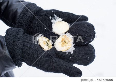 Gold coins bitcoin in mittens in winter. Crypto 38139600