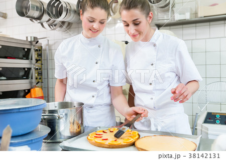 Women putting fruit on cakes in pastry bakery 38142131