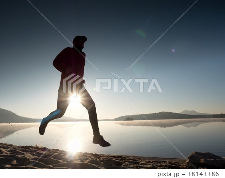 Exercising on the beach at sunset, sun at horizon Exercising on the beach at sunset, sun at horizon 38143386