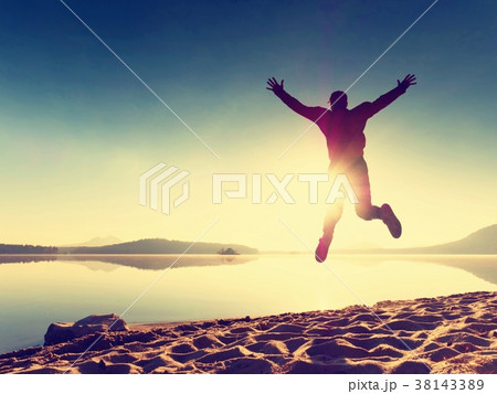 Adult crazy man jumps near water on against sun Adult crazy man jumps near water on against sun 38143389