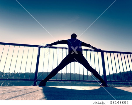 Runner body stretching on bridge path.Sun outlines 38143392