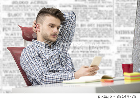 Young happy businessman smiling while reading his 38144778