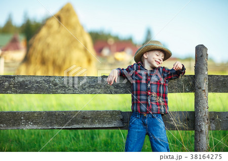 Smiling little boy leaned on wooden fence 38164275