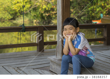 Asian girl with big smile sitting on wood floor 38168357
