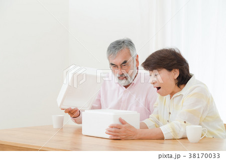 小包を開けて困惑する老夫婦　配送トラブル　送りつけサギ　シニア　シルバー世代　おじいさんとおばあさん 38170033