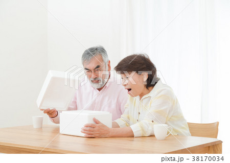 小包を開けて困惑する老夫婦　配送トラブル　送りつけサギ　シニア　シルバー世代　おじいさんとおばあさん 38170034
