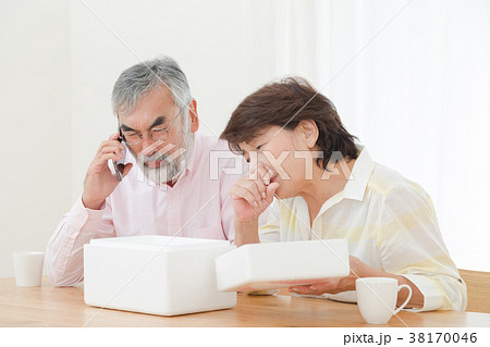小包を開けて困惑する老夫婦　配送トラブル　送りつけサギ　シニア　シルバー世代　おじいさんとおばあさん 38170046