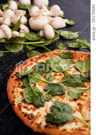 Pizza covered with spinach leaves next to 38170080