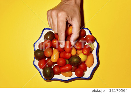 man picking a cherry tomato from a plate man picking a cherry tomato from a plate 38170564