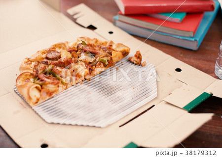 Piece of Pizza on table. Pizza on table with books Piece of Pizza on table. Pizza on table with books 38179312