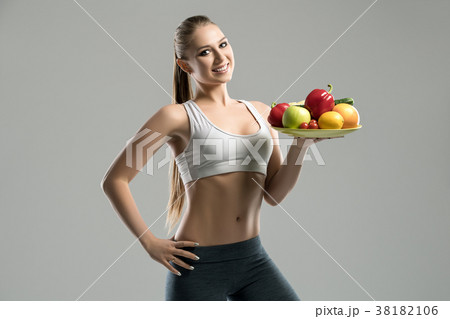 Beautiful young sportswoman holding plate of fruit Beautiful young sportswoman holding plate of fruit 38182106