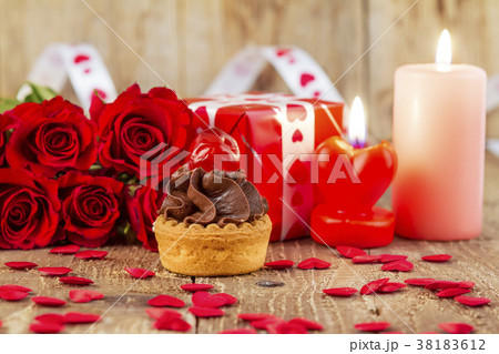 Cupcake with cherry in front of red roses Cupcake with cherry in front of red roses 38183612