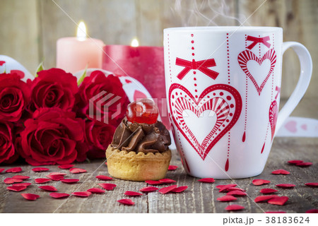 Cupcake with cherry in front of bouquet of roses Cupcake with cherry in front of bouquet of roses 38183624
