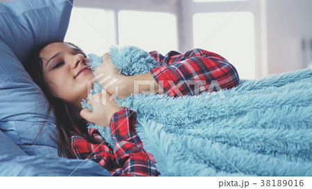 Sleepy young woman lying in bed waking up and 38189016