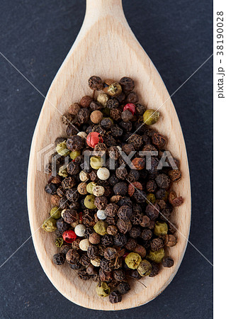black pepper peas in a spoon on a stone background 38190028