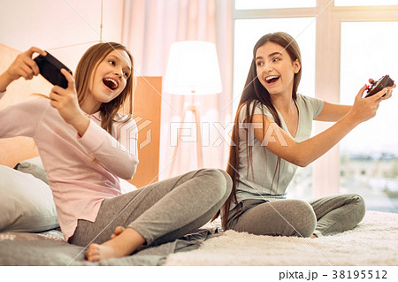 Upbeat teenage sisters playing video games 38195512
