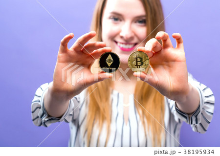 Woman holding physical bitcoin and ethereum coins 38195934