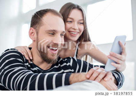Delighted couple laughing while using the phone Delighted couple laughing while using the phone 38197855