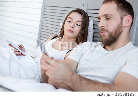 Serious woman looking what her man typing on his 38198135