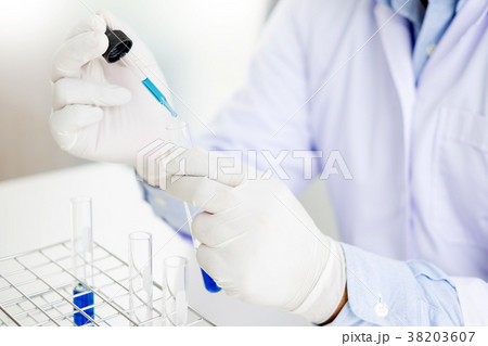 Scientist dropping adds the   reagent from the dropper to test t 38203607