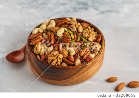 A variety of nuts and seeds in a wooden bowl A variety of nuts and seeds in a wooden bowl 38209055